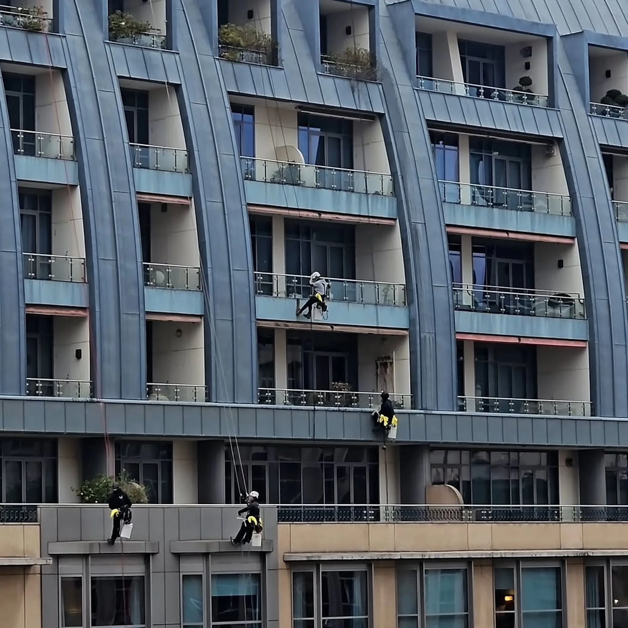 workers suspended on ropes cleaning building