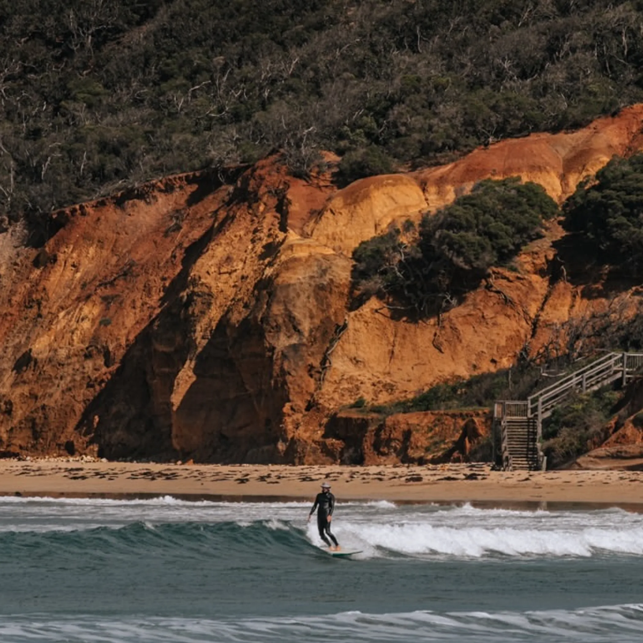 surfer, beach, eroding cliffs, and stairs